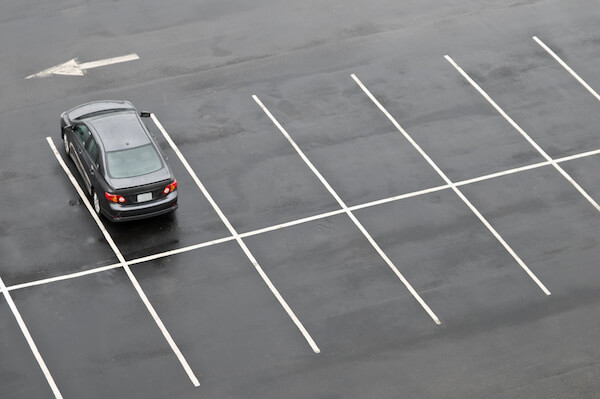 Single car in otherwise empty parking lot, in the rain