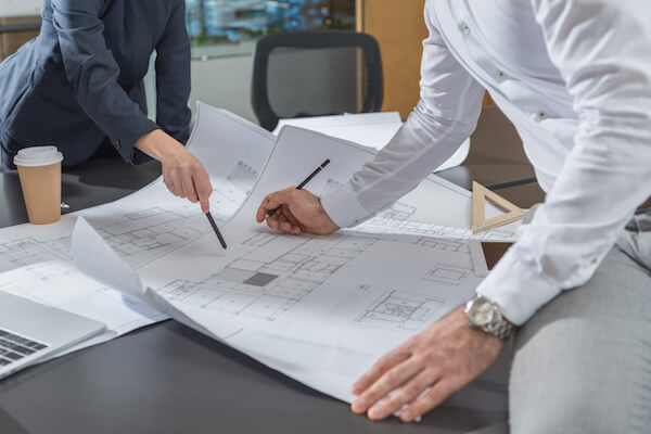 cropped shot of stylish architects working with building plans together at office