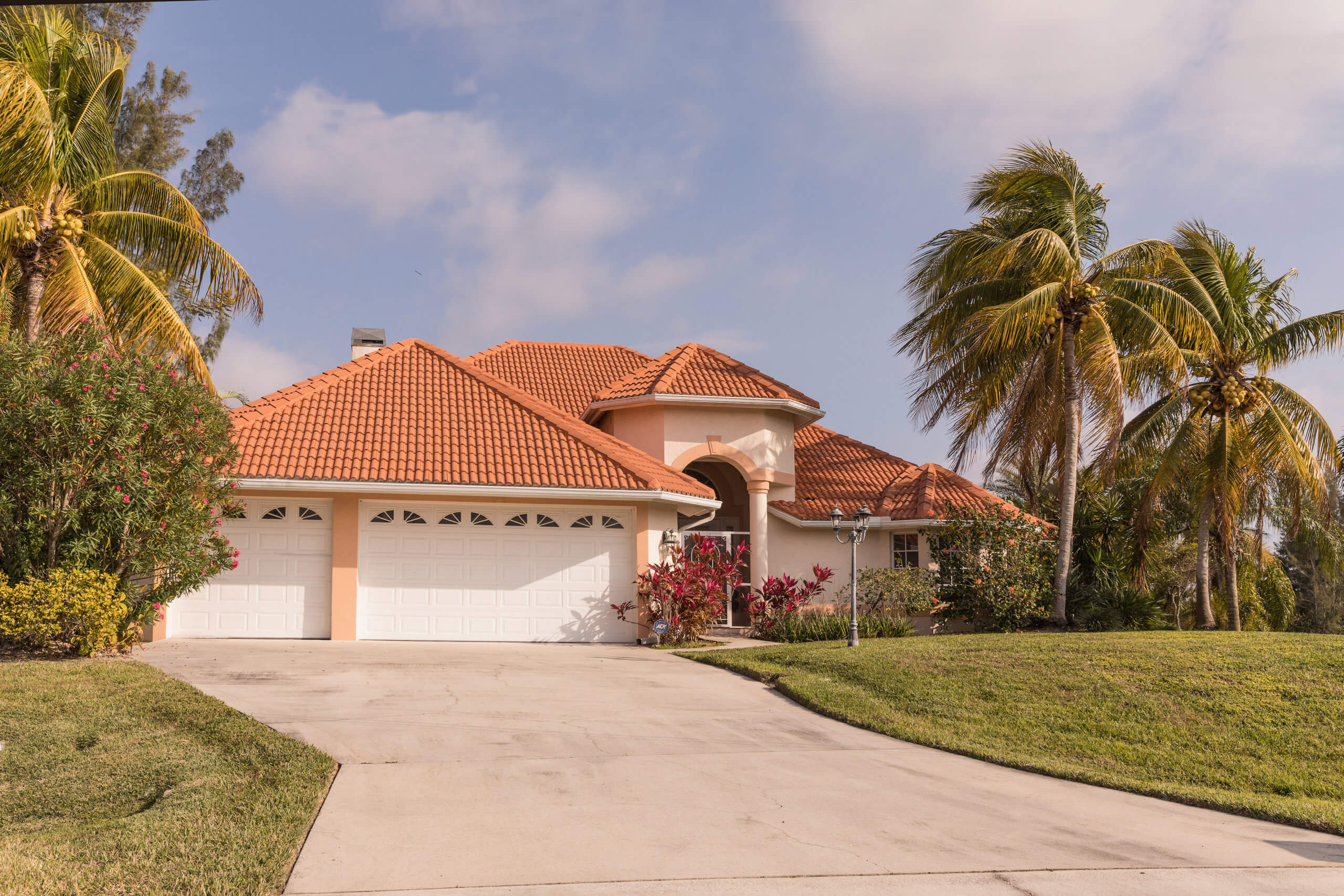 waterproofing your property Typical Southwest Florida concrete block and stucco home in the countryside with palm trees, tropical plants and flowers, grass lawn and pine trees. Florida. South Florida single family house